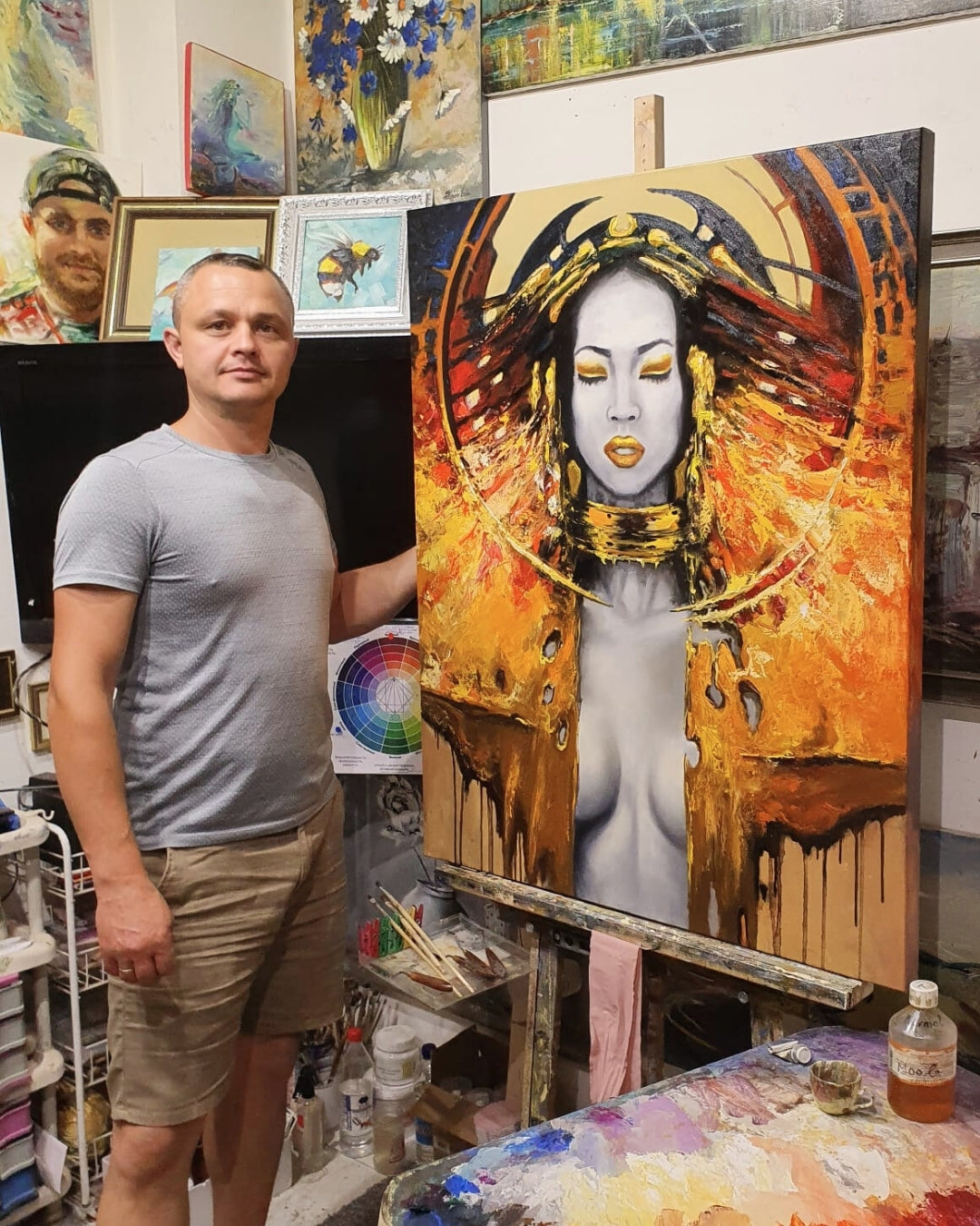 Ein ausdrucksstarkes Ölgemälde von Vadim Lazarev (Träume), das eine Frau mit geschlossenen Augen zeigt. Ihr Gesicht ist sanft modelliert, während ihr Körper und Gewand in kräftigen Gold-, Rot- und Schwarztönen mit fließenden Strukturen und glänzenden Akzenten gestaltet sind. Die Komposition strahlt eine spirituelle und kraftvolle Aura aus, verstärkt durch abstrakte Elemente und goldene Details. Ein hypnotisches Kunstwerk mit tiefer Symbolik. Mit im Bild: der Künstler selbst.