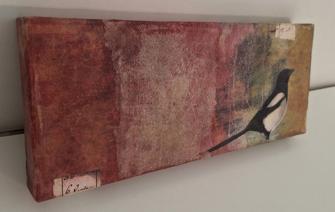 Collage „Elster“ von Monika Schiwy-Jessen, Querformat auf Box, handgefärbte Papiere und Stoffe, Naturmotiv, 10x24,5x2,5 cm.