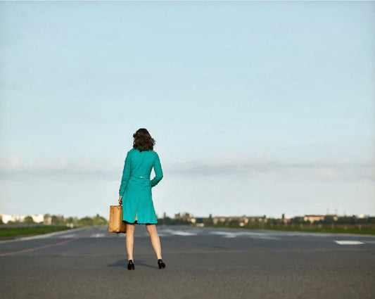 Das Kunstwerk "War's das?" des Künstlers nostrokesbitte ist ein digitales Gemälde im Stil des Fotorealismus. Es zeigt eine Frau von hinten, die in der Mitte eines breiten, asphaltierten Weges steht und einen kleinen Koffer hält. Sie trägt einen türkisfarbenen Mantel und blickt auf einen weiten, klaren Himmel. Die gesamte Szene ist in den sanften, gedeckten Farbtönen einer Morgenstimmung gehalten. Das Gemälde wurde auf Leinwand gedruckt und ist in limitierter Auflage in der Online-Galerie FEMARTSPACE erhält