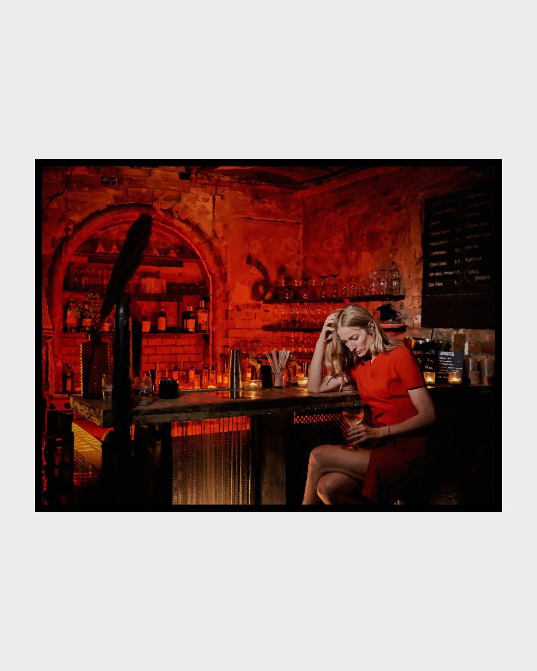 Das fotorealistische Digitalgemälde "Chablis bei Schlamassel" von nostrokesbitte zeigt eine blonde Frau im roten Kleid, die melancholisch an einer rot beleuchteten Bar sitzt und ein Glas Wein hält. Das Werk ist in limitierter Auflage bei FEMARTSPACE erhältlich.