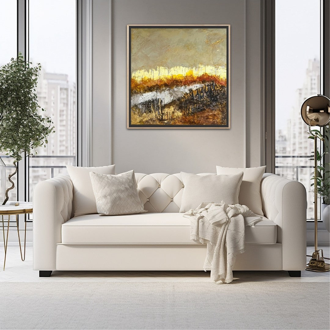 Zwischen Glut und Asche" von Sigrid Bautze-Klinder als Blickfang in einem modernen Wohnzimmer. Das strukturreiche, quadratische Acrylgemälde hängt über einem cremefarbenen, gesteppten Sofa vor einer hellgrauen Wand. Der Gold-Ocker-Ton des Himmels und die warmen Akzente der Glut im Bild ergänzen die sanften, hellen Farben des Raumes. Große Fenster bieten einen Blick auf eine städtische Skyline.