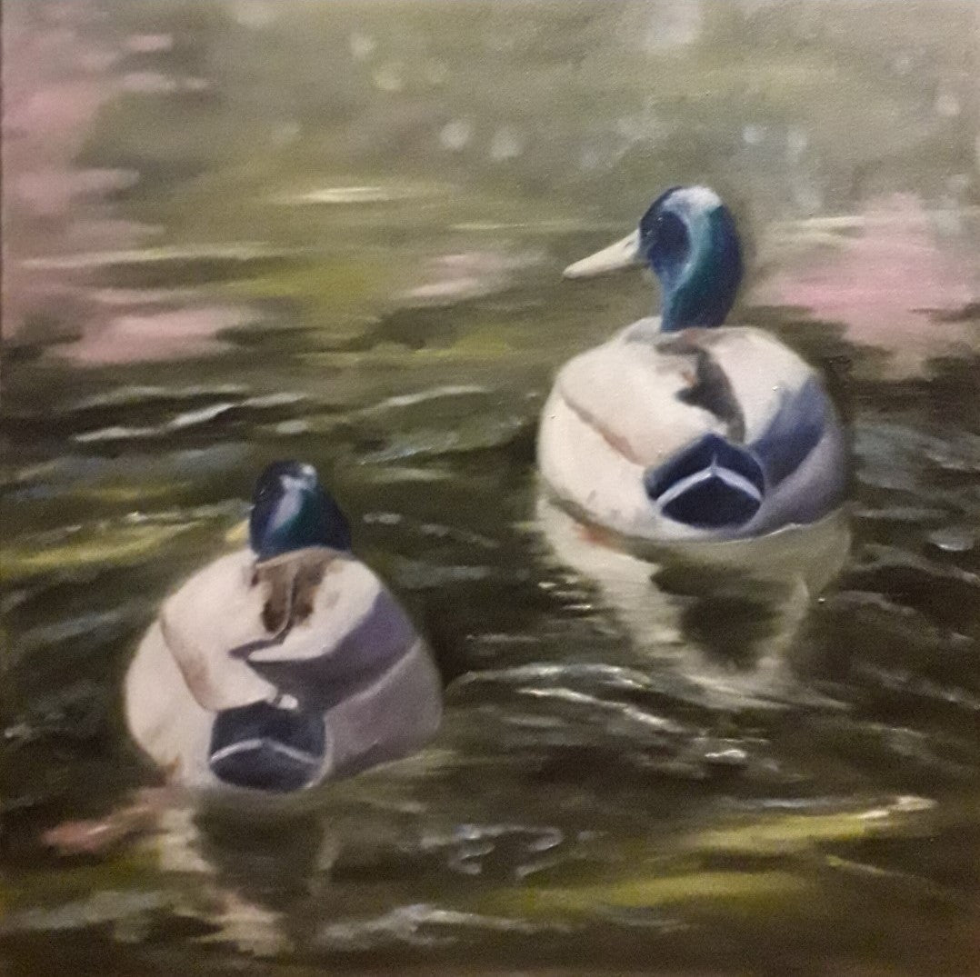 Zwei Stockenten schwimmen auf einem Teich, ihre Rücken dem Betrachter zugewandt. Die Enten sind in Weiß- und Blautönen gehalten und spiegeln sich im leicht trüben Wasser. Der Hintergrund zeigt verschwommenes Grün und Braun, was auf Bäume und Uferbewuchs hindeutet. Ölgemälde von Anke Dinkelbach, Künstlerin bei FemArtSPACE.