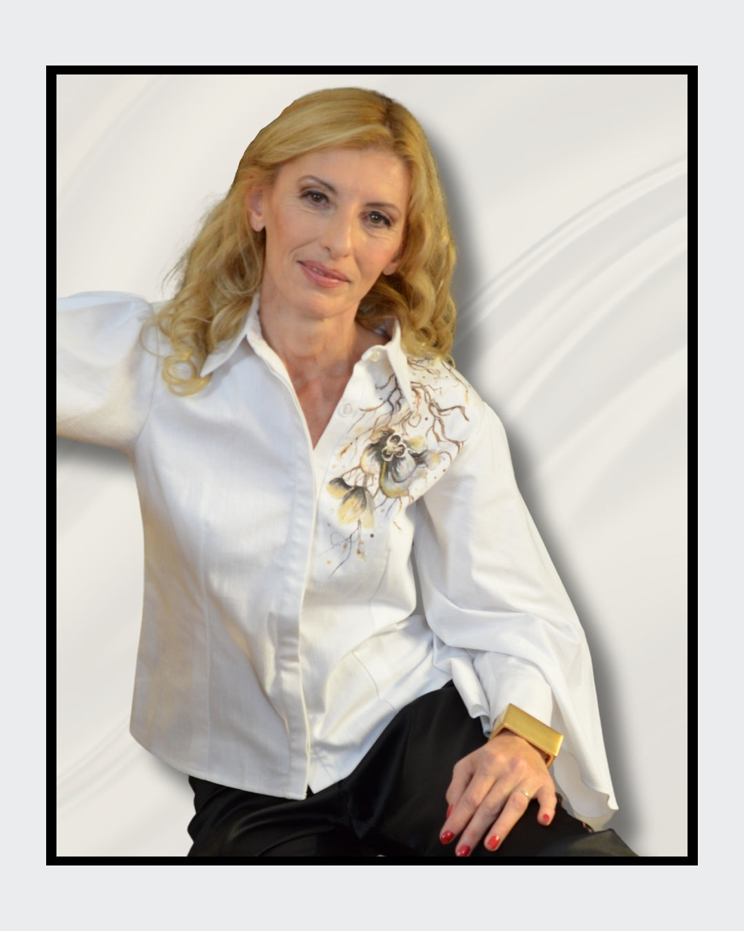 Fashionart von Kaja Schäfer für FemArtSPACE: Nahaufnahme der Frau. Weiße Seidenbluse mit floralem Motiv, blonde wellige Haare, goldener Armreif und roter Nagellack. Cremiger Hintergrund mit fließenden Stoffen.