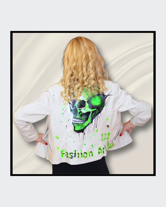 Fashionart von Kaja Schäfer: Eine Person trägt eine handbemalte weiße Bikerjacke mit grünem Totenkopf-Motiv. Dieses Kunstwerk vereint mutige Farben und einzigartigen Stil, im Artshop von “FemArtSPACE”.