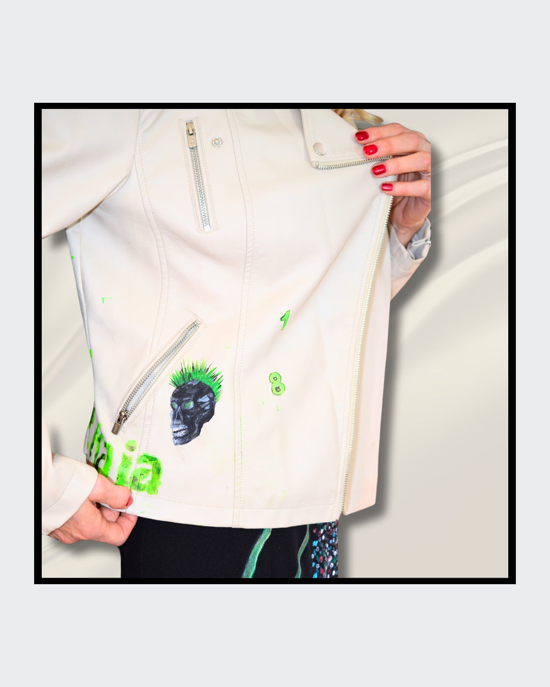 Fashionart von Kaja Schäfer: Eine Person trägt eine handbemalte weiße Bikerjacke mit grünem Totenkopf-Motiv. Dieses Kunstwerk vereint mutige Farben und einzigartigen Stil, im Artshop von “FemArtSPACE”.