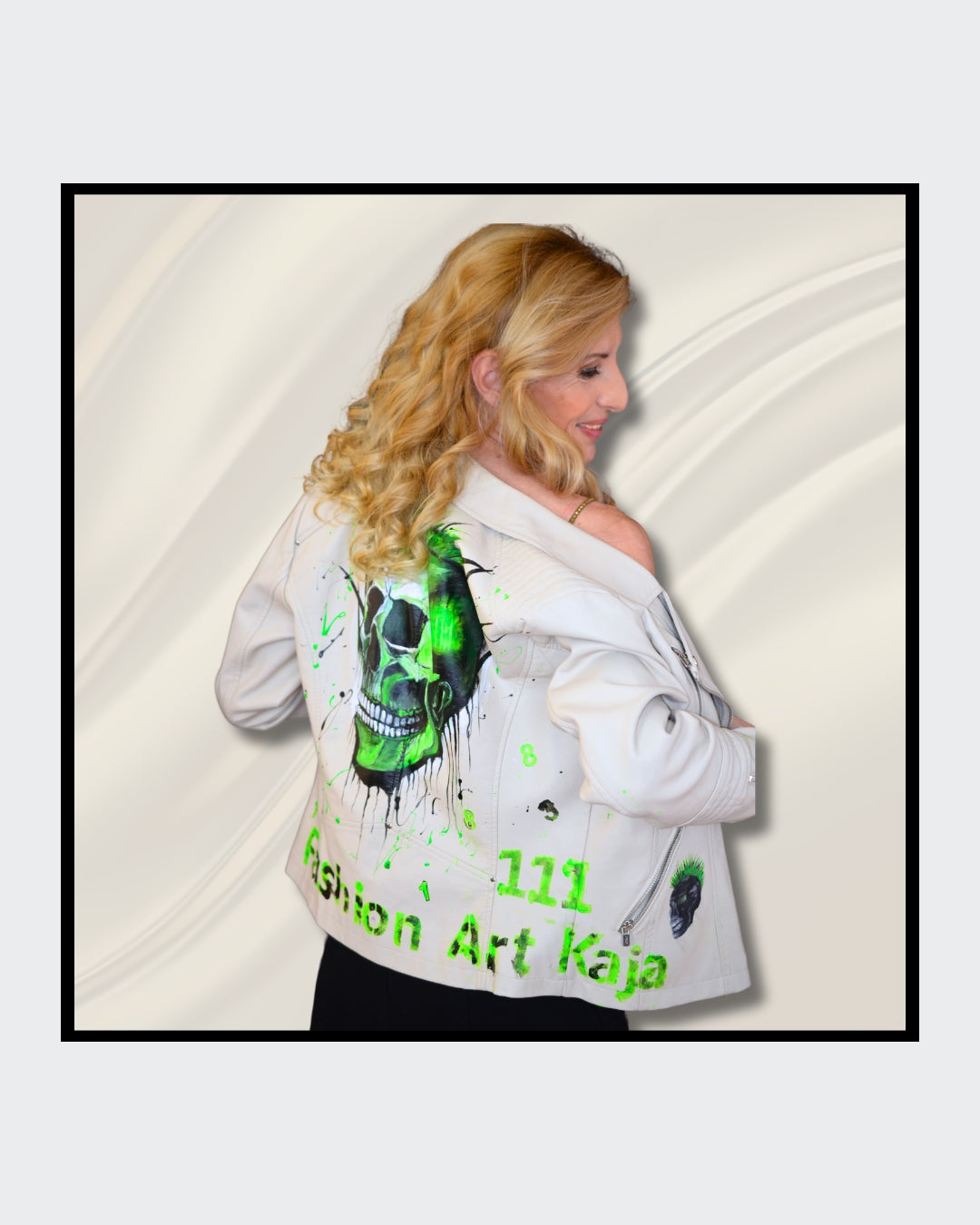 Fashionart von Kaja Schäfer: Eine Person trägt eine handbemalte weiße Bikerjacke mit grünem Totenkopf-Motiv. Das Gesicht ist verdeckt. Dieses Kunstwerk vereint mutige Farben und einzigartigen Stil, im Artshop von “FemArtSPACE”.