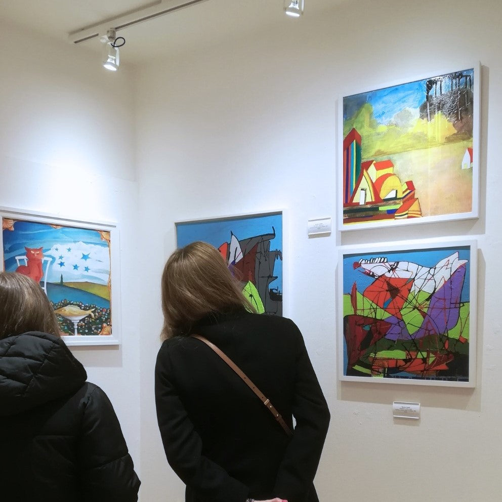 Kunstausstellung in Udine, zwei Personen von hinten, die Bilder an der Wand betrachten.