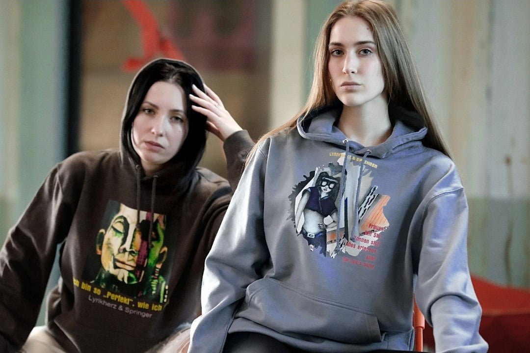 Models, die Unisex-Hoodies tragen mit Kängurutasche und Kapuze. Auf der Vorderseite ist ein Kunstwerk gedruckt. Kollektion von Lyrikherz & Springer. Erhältlich bei FEMARTSPACE.