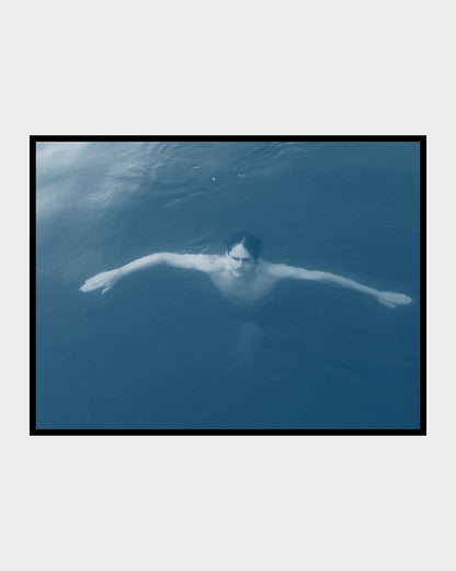 
Das Kunstwerk "Christianisierung Brandenburgs" des Künstlers nostrokesbitte zeigt ein digitales Gemälde im fotorealistischen Stil. Es ist ein Porträt, das eine Person von oben im Wasser liegend darstellt. Die Person blickt direkt auf den Betrachter und hat die Arme ausgebreitet. Das Bild ist in kühlen, bläulichen Farbtönen gehalten, die die Wasseroberfläche darstellen. Das Werk wurde auf Leinwand gedruckt und ist in einer limitierten Edition über die Online-Galerie FEMARTSPACE erhältlich.