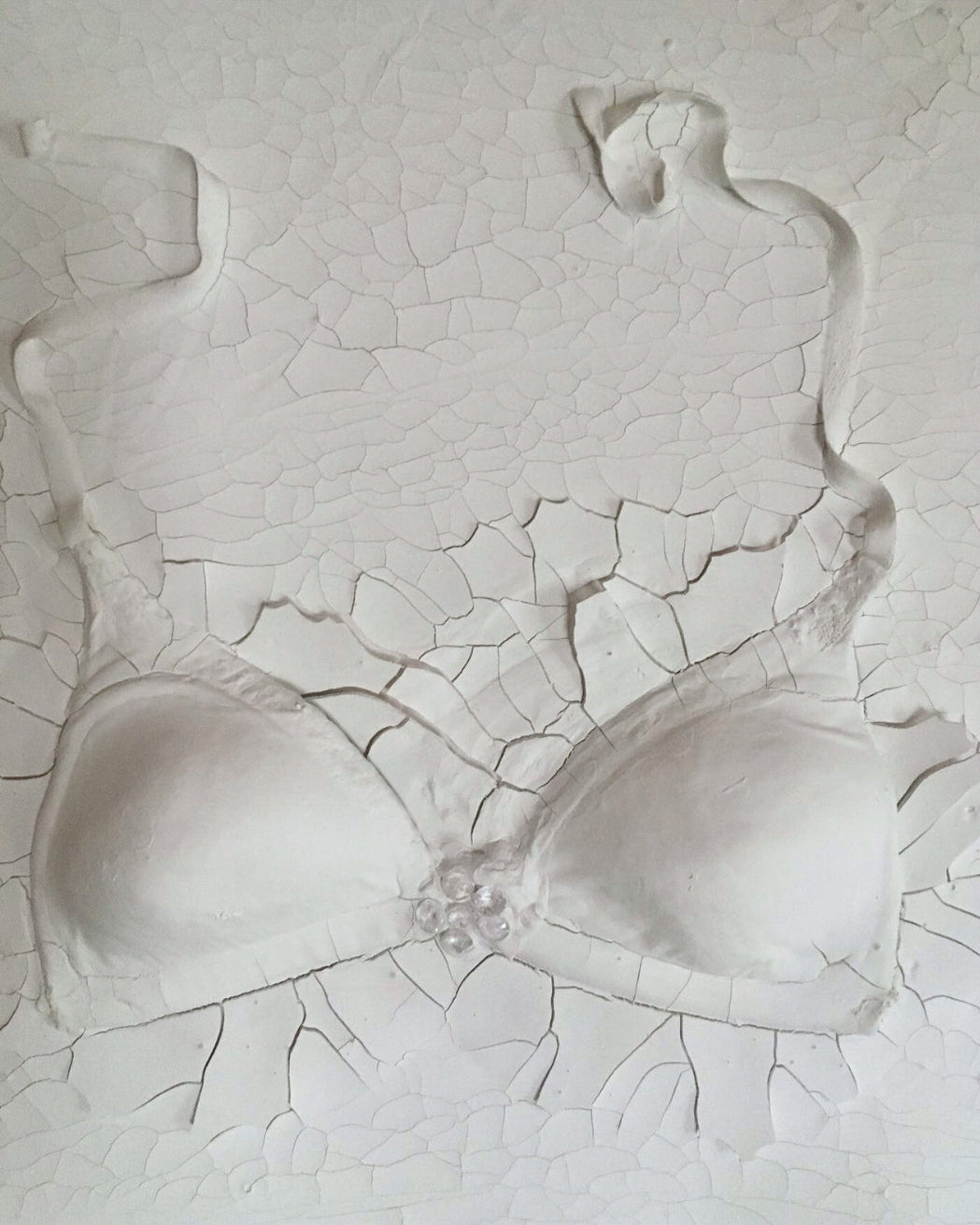 Gemälde "Verhüllte Wahrheit" von Federica, Textil auf Leinwand mit Acryl, 80x60 cm. Dreidimensionales Textilobjekt in Form eines Büstenhalters auf gerissener Leinwand in Weiß- und Grautönen.