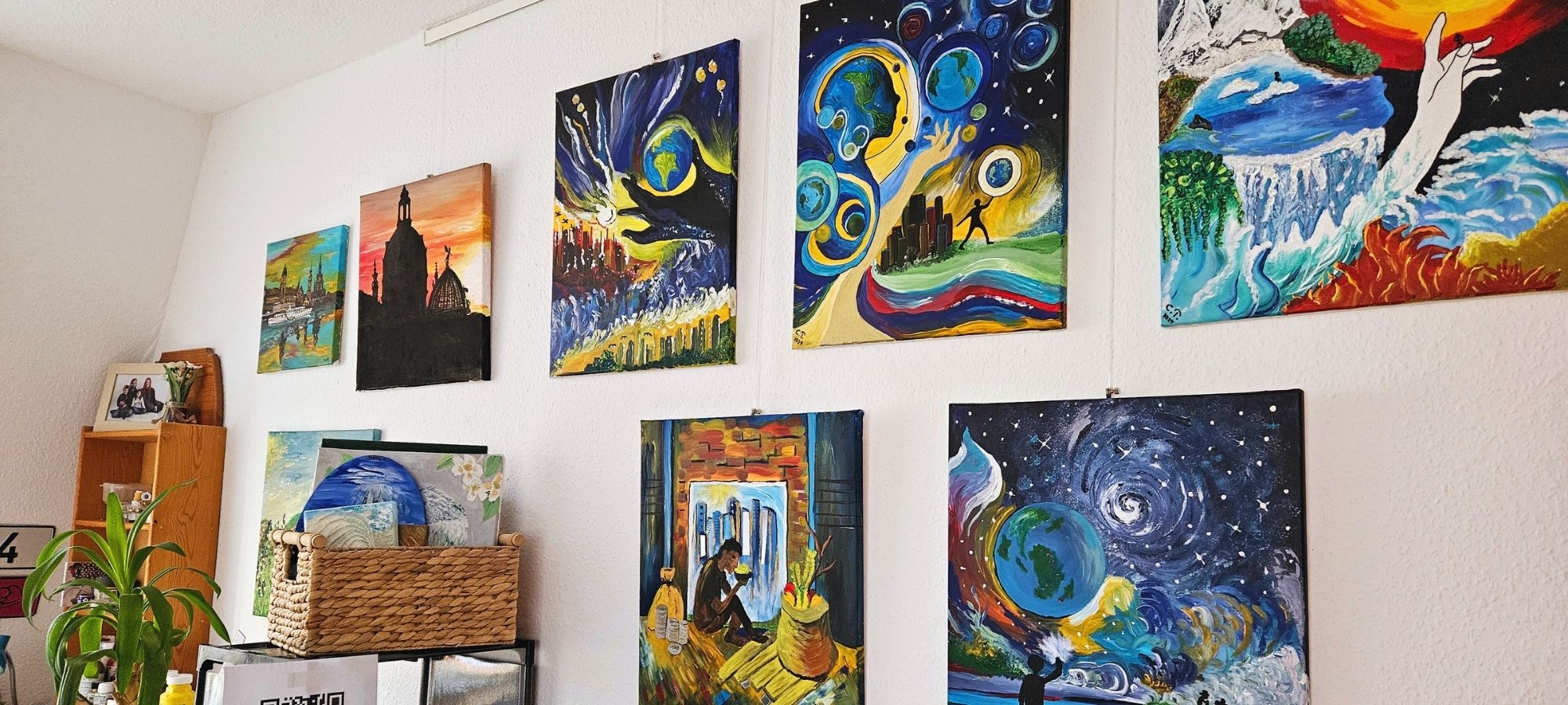 Headerbild der Künstlerseite von Carina Teufel. An der Wand hängen mehrere farbenfrohen Werke von ihr.