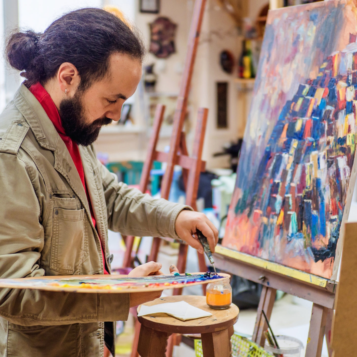 Künstler bei FemArtSPACE arbeitet an einer farbenfrohen abstrakten Leinwand, umgeben von Kunstmaterialien und Staffeleien, die den kreativen Geist der Online-Kunstgemeinschaft verkörpern.