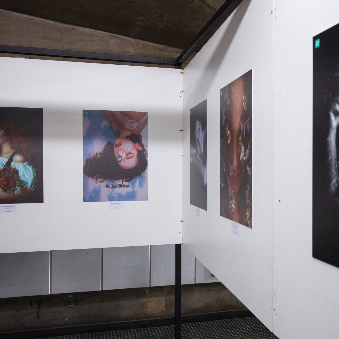 Ausstellungsansicht bei FemArtSPACE mit drei Kunstwerken; das zentrale Stück zeigt ein Nahaufnahme-Porträt mit lebendiger Gesichtsbemalung, flankiert von zwei weiteren Werken in einer modernen Galerie mit industriellen Elementen.